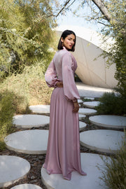 Woman in a pink dress standing on circular stone paths with greenery around.